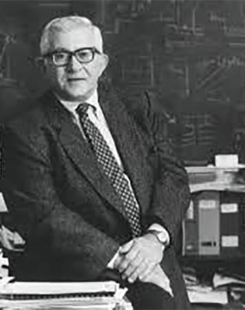 A man in suit and tie sitting at desk.